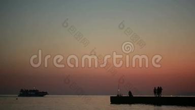 一群人在大海的背景上。 日落时的剪影。 夏季海滩
